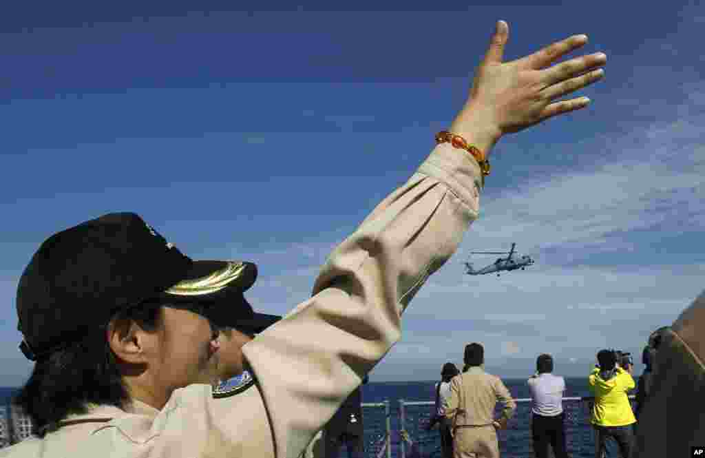 An officer flashes hand signals to a passing helicopter from the stern of a Taiwanese Kidd-class destroyer during exercises off the southern city of Kaohsiung,Taiwan, May 16, 2013. 