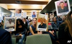 Bea Abbott, center, joins other attendees in holding up placards bearing the photographs of people who went missing while trying to cross the border from Mexico into the United States during a hearing held by the Inter-American Commission on Human Rights, Oct. 5, 2018, at the University of Colorado in Boulder, Colo.