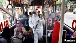 Seorang petugas melakukan penyemprotan disinfektan untuk mencegah perebakan virus corona di sebuah bus di Surabaya, Jawa Timur hari Minggu (22/3). 