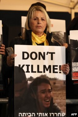 FILE -A woman holds a placard reading "don't kill me" in Tel Aviv on January 13, 2024.