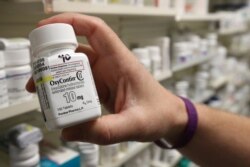 FILE - A pharmacist holds a bottle OxyContin made by Purdue Pharma at a pharmacy in Provo, Utah, May 9, 2019.