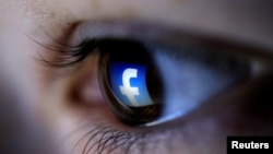 A picture illustration shows a Facebook logo reflected in a person's eye, in Zenica