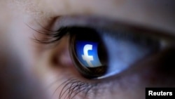 A picture illustration shows a Facebook logo reflected in a person's eye, in Zenica