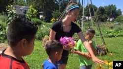 In this photo provided by Ginny Hughes, members of the Troy Kids' Garden Learning Community make bouquets at Troy Gardens in Madison, Wis. (Ginny Hughes via AP)