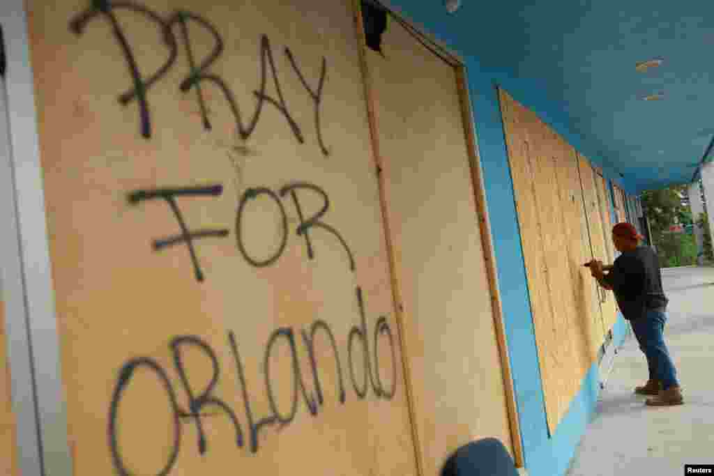 Una persona asegura planchas de madera a las vidrieras de un comercio y se lee que alguien escribió: &quot;Oren por Orlando&quot;, en Orlando, Florida, el 8 de octubre de 2024.