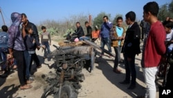 FILE - In this Monday, Nov. 12, 2018 file photo, Palestinians inspect a vehicle that was destroyed in an Israeli raid that killed seven Hamas Palestinian militants, including a local Hamas commander, late Sunday, east of Khan Younis, southern Gaza Strip.