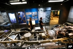 Workers walk past a mock-up of an assembly line manufacturing army jeeps as part of the permanent exhibit "Salute to the Home Front" at the National World War II Museum.
