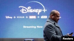 Un hombre mira su teléfono cuando pasa por una pantalla que anuncia el servicio de transmisión de Walt Disney Disney + en la ciudad de Nueva York, el 12 de noviembre de 2019.
