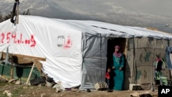 FILE - A Syrian refugee stands outside her tent in a refugee camp in the eastern town of Houch al-Harimeh, Lebanon.