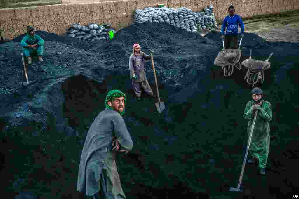 Hazara workers prepare to load coal onto a truck near the site where the Salsal Buddha statue once stood before being destroyed by the Taliban in March 2001, in Bamiyan province, Afghanistan, Oct. 3, 2021.