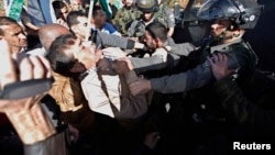 Palestinian minister Ziad Abu Ein (L) scuffles with an Israeli border policeman near the West Bank city of Ramallah, Dec. 10, 2014.