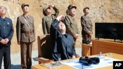 Лидер Северной Кореи Ким Чен Ын, в центре, наблюдает за запуском ракетыКореи. 