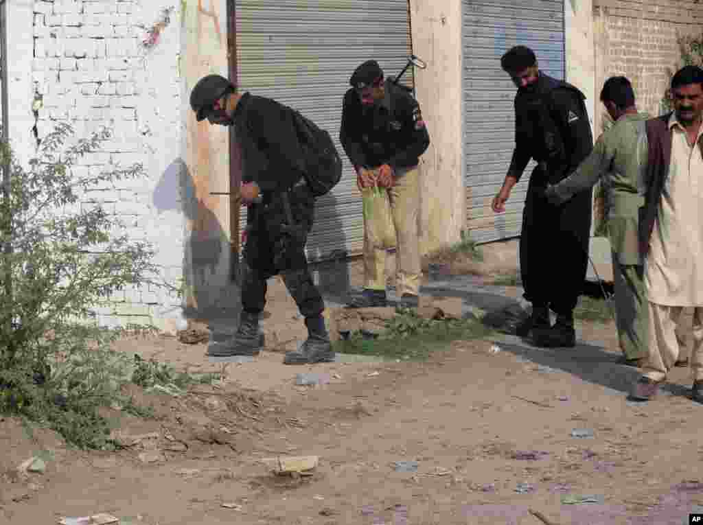 Pakistani police officers collect evidence from the site of a bomb blast in Dera Ismail Khan, Pakistan on Saturday, Nov. 24, 2012. A roadside bomb killed several people, including children, and wounded dozens of others at a Shiite Muslim procession in northwestern Pakistan, police said. (AP Photo/Kashif Naveed)