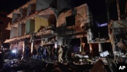 FILE - People gather in the aftermath of a multiple explosive attack in the Sayyida Zeinab area, 10 kilometers south of Damascus, Syria, Feb. 21, 2016. The Islamic State group claimed responsibility for a triple blast in the Shi'ite suburb.