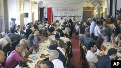 Prominent opposition figures and critics of Syrian President Bashar al-Assad's regime gather for a meeting, with attached banner in Arabic that reads 'Syria is for everybody, in the shadow of a democratic civil state,' in Damascus, Syria, June 27, 2011