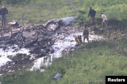 Israeli security forces walk next to the remains of an F-16 Israeli warplane near the Israeli village of Harduf, Israel, Feb. 10, 2018.