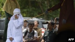 Tjia Nyuk Hwa, 45, an Indonesian Christian is publicly flogged outside a mosque in Banda Aceh on February 27, 2018, for playing a children's entertainment game seen as violating Islamic law.