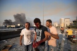 Un hombre herido en la masiva explosión que sacudió el centro de Beirut, Líbano, es ayudado por otras personas, el martes 4 de agosto de 2020.