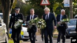 Perdana Menteri Inggris Boris Johnson dan pemimpin Partai Buruh Keir Starmer, kedua dari kiri, membawa bunga saat mereka tiba di lokasi di mana anggota parlemen David Amess ditikam Jumat, di Leigh-on-Sea, Essex, Inggris, 16 Oktober , 2021. (Foto: AP)