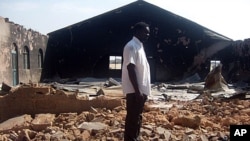 A file picture taken on January 24, 2010, shows a Christian resident of the Nigerian city of Jos standing near a church burnt in ongoing sectarian violence.