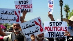 FILE - Supporter of the leader of the Ennahdha party Rached Ghannouchi, hold placards as they stage a protest at Tunisia's anti-terrorism unit in Tunis, Tunisia, Tuesday, July 19, 2022. 