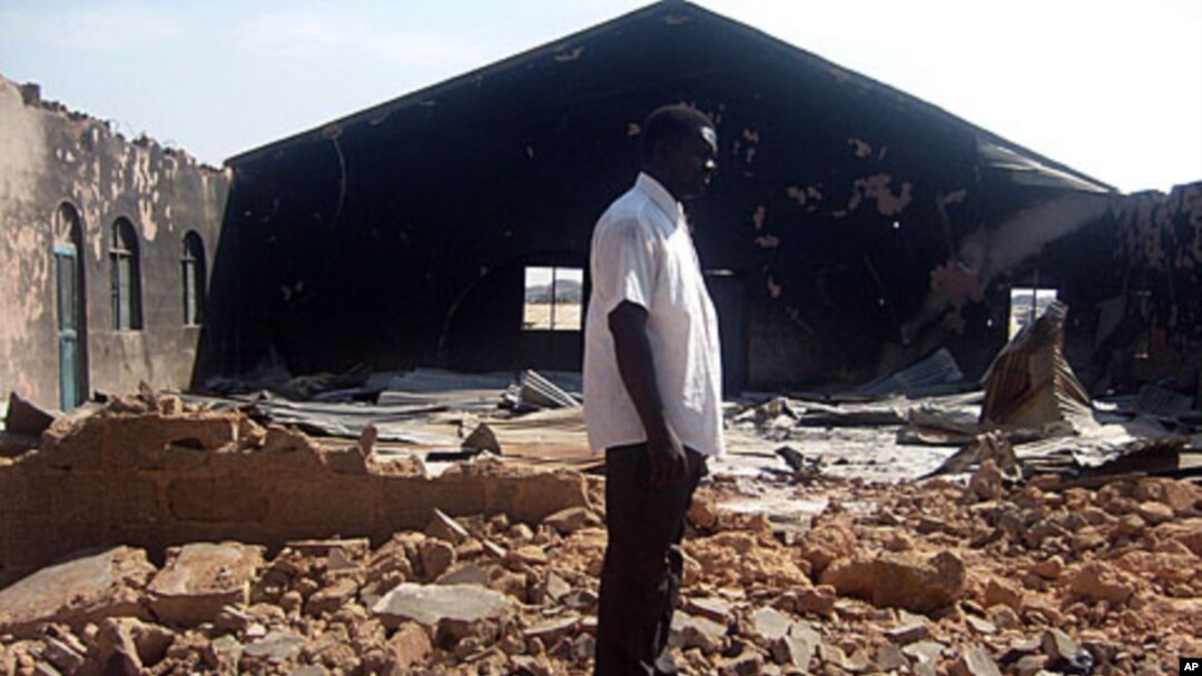 A file picture taken on January 24, 2010, shows a Christian resident of the Nigerian city of Jos standing near a church burnt in ongoing sectarian violence.