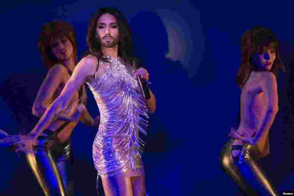 Conchita Wurst (giữa), người chuyển giới thành nữ để râu và là quán quân cuộc thi Eurovision, biểu diễn bài hát "True Love?" trên sân khấu cùng những vũ công ngực trần trong một buổi diễn tập cho chương trình "Desirs" tại hội quán ca nhạc Crazy Horse ở Paris, ngày 30 tháng 10, 2014. 