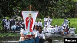 FILE - Roman Catholic pilgrims display a banner depicting Jesus Christ as they travel in a boat during an annual river procession along the Caraparu River in Santa Izabel do Para, in the Amazon jungle, Dec. 8, 2012.