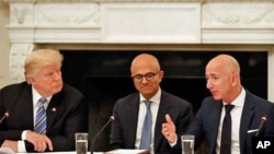 President Donald Trump, left, and Satya Nadella, Chief Executive Officer of Microsoft, center, listen as Jeff Bezos, Chief Executive Officer of Amazon, speaks during an American Technology Council roundtable in the State Dinning Room of the White House.