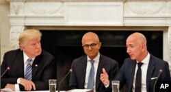 FILE - President Donald Trump, left, and Satya Nadella, Chief Executive Officer of Microsoft, center, listen as Jeff Bezos, Chief Executive Officer of Amazon, speaks during an American Technology Council roundtable in the State Dinning Room of the White House, June 19, 2017.
