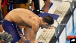 Michael Phelps shakes hands with Nathan Adrian from the United States as they celebrate after winning the gold medal in the men's 4x100-meter freestyle final during the swimming competitions at the 2016 Summer Olympics, Sunday, Aug. 7, 