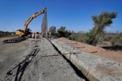 Government contractors erect a section of border wall along the Colorado River, Sept. 10, 2019, in Yuma, Ariz. Construction began as federal officials revealed a list of Defense Department projects to be cut to pay for the wall.