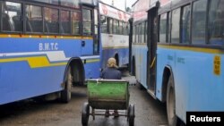 FILE - A porter sits in his pushcart as he waits for customers in between passenger buses at a municipal bus terminal in Bengaluru, India, Sept. 8, 2015. The first bus of its kind hit the streets of the Indian capital, New Delhi, Wednesday equipped with safety features to increase security for women.