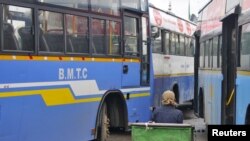 FILE - A porter sits in his pushcart as he waits for customers in between passenger buses at a municipal bus terminal in Bengaluru, India, September 8, 2015. 