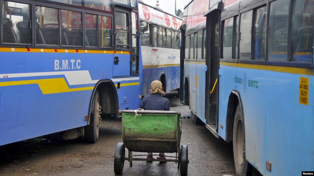 FILE - A porter sits in his pushcart as he waits for customers in between passenger buses at a municipal bus terminal in Bengaluru, India, Sept. 8, 2015. The first bus of its kind hit the streets of the Indian capital, New Delhi, Wednesday equipped with safety features to increase security for women.