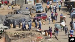 La police anti-émeute patrouille près d'un marché très fréquenté malgré le confinement à Harare au Zimbabwe, le 7 avril 2020.