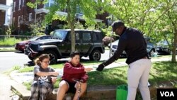 Adeoye Owolewa, U.S. 'shadow' representative for Washington, D.C., collects forms from two young Washington residents signing up for notifications about COVID-19 vaccine availability. (Betty Ayoub/VOA)