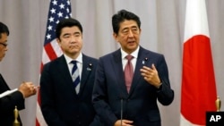 FILE - Japanese Prime Minister Shinzo Abe, right, answers questions from the media after meeting with then U.S. President-elect Donald Trump, Nov. 17, 2016. 