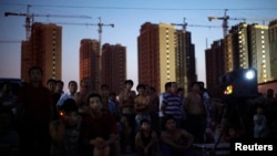 Migrant construction workers watch an open air movie near their dormitories after a shift at a residential construction site in Shanghai, July 15, 2013.