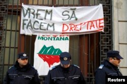 FILE - Banners are seen behind gendarmes after environmentalist activists occupied the People Advocate's headquarters in Bucharest, Dec. 10, 2013. They are protesting against a Canadian company's project to set up Europe's biggest open cast gold mine in Romania.