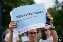 FILE - A woman holds high a sign that reads "#SaveOurAllies" at a rally calling for the evacuation of Afghan allies, July 1, 2021.