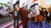 FILE - Iraqi people walk on a U.S. flag in a protest after an airstrike at the headquarters of Kataib Hezbollah militia group in Qaim, in the holy city of Najaf, Iraq, Dec. 30, 2019. 