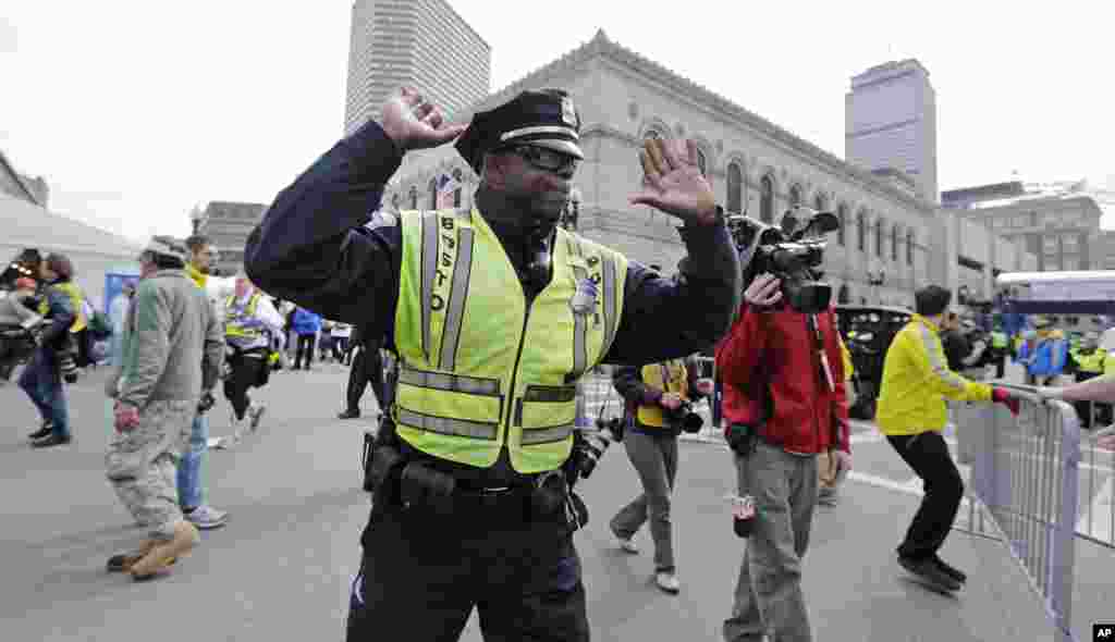 A police officer clears Boylston Street following an explosion at the finish line of the 2013 Boston Marathon, April 15, 2013.