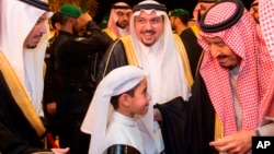 FILE - In this photo released by Saudi Press Agency, SPA, Saudi King Salman greets a boy during his visit to Qassim province in Qassim, Saudi Arabia, Nov. 7, 2018.