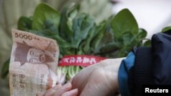 ແມ່ບ້ານຊາວເກົາຫຼີໃຕ້ຄົນນຶ່ງ ຊື້ຜັກ ຢູ່ຕະຫຼາດແຫ່ງນຶ່ງ ໃນນະຄອນຫລວງ ໂຊລ.