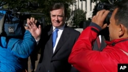 Paul Manafort makes his way through television cameras as he walks from Federal District Court in Washington, Oct. 30, 2017. 