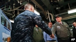 Presidente Donald Trump saluda al oficial de primera clase, John Thompson durante su visita al portaaviones Gerald R. Ford.