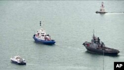 This video grab provided by the Krym 24 tv station via AP Television shows a seized Ukrainian ship, right, is towed by a Russian coast guard boat out of the port in Kerch, Crimea, Nov. 17, 2019. 