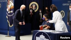 在白宫举行的纪念美国接种5千万新冠疫苗的活动上,拜登总统看着琳达·布西接种第一剂疫苗。(2021年2月25日)