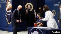 President Joe Biden watches as Linda Bussey receives the first round of the COVID-19 vaccine during an event to commemorate the 50 millionth vaccination at the White House, Feb. 25, 2021.